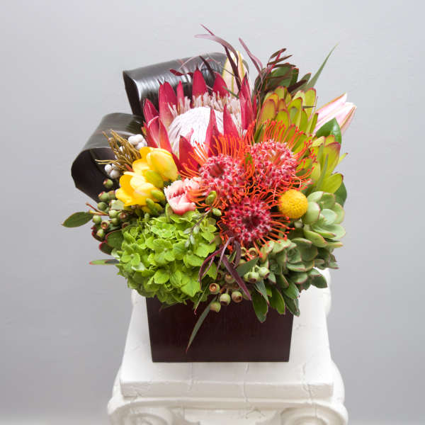 Colorful tropical bouquet in a dark square vase
