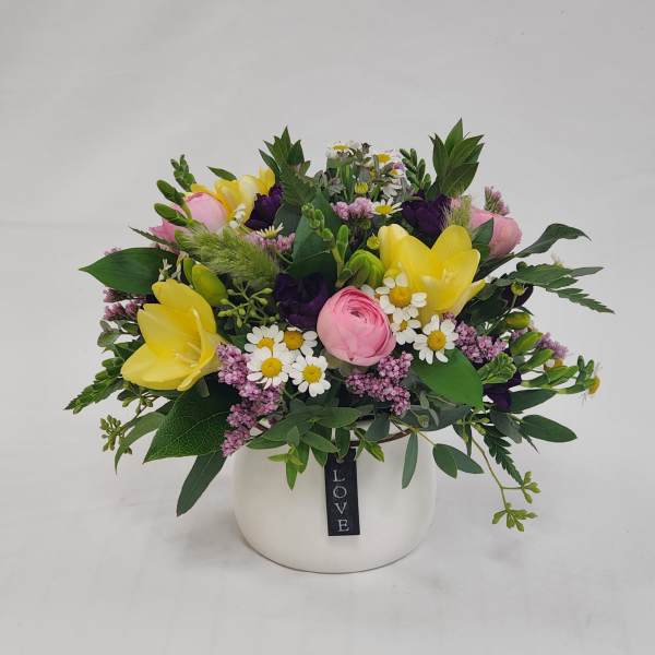Mixed bouquet of yellow and pink flowers in a white vase