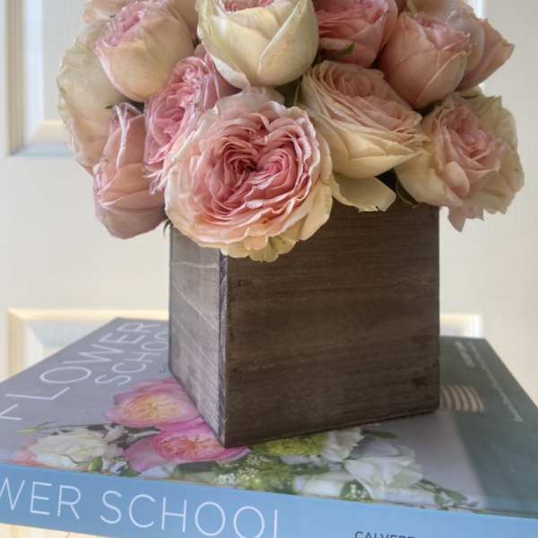 Pink and cream roses arranged in a wooden box