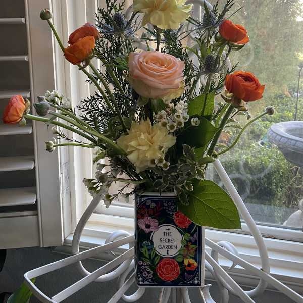 Mixed bouquet of roses, ranunculus, and blue thistle in a decorative box