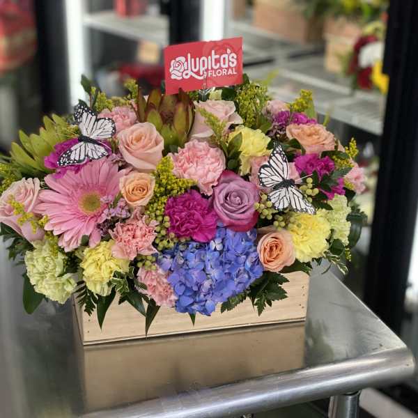 Mixed bouquet in a wooden box with pink, yellow, purple, and blue flowers