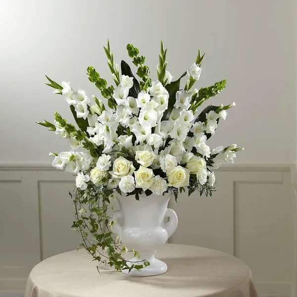 White floral arrangement in a white urn vase