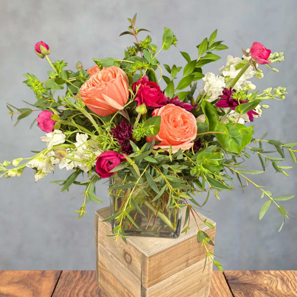 Mixed bouquet of peach and pink roses in a glass vase