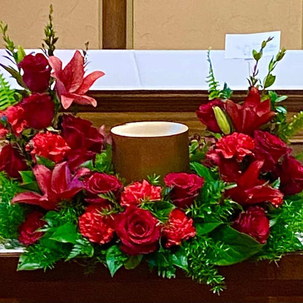 Red floral altar arrangement with a central candle holder