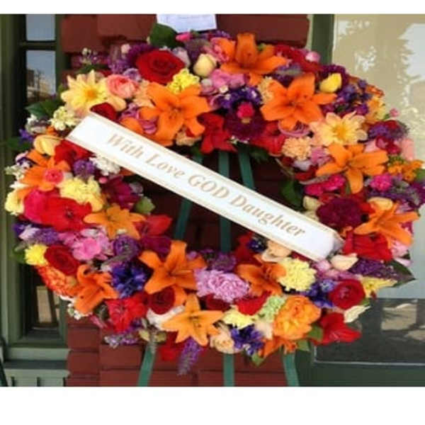 Large colorful funeral wreath with a white memorial ribbon