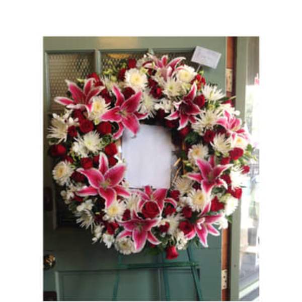 Heart-shaped funeral wreath with pink lilies, red roses, and white flowers