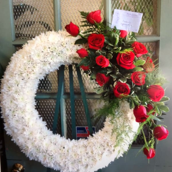 White floral wreath with red roses on a stand