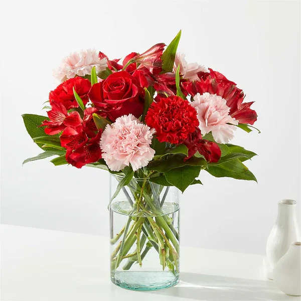 Red roses and pink carnations in a clear glass vase