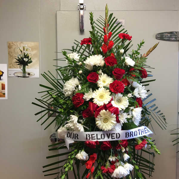 Standing red and white funeral spray with ribbon tribute