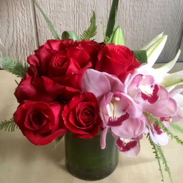 Red roses and pink orchids in a green vase
