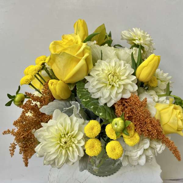 Yellow roses and white dahlias in a glass vase
