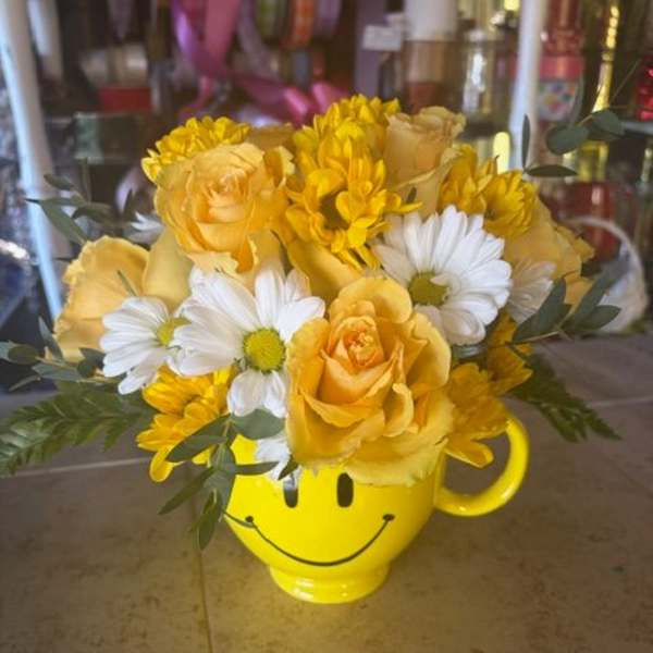 Yellow roses and white daisies in a smiley-face mug
