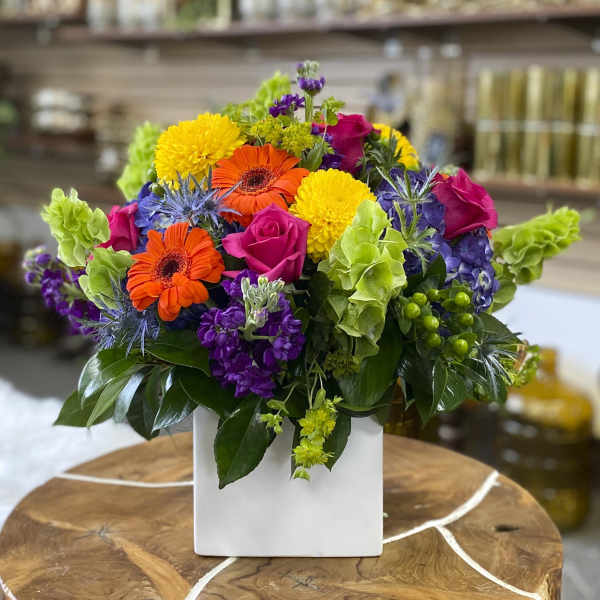 Colorful mixed flower arrangement in a white square vase