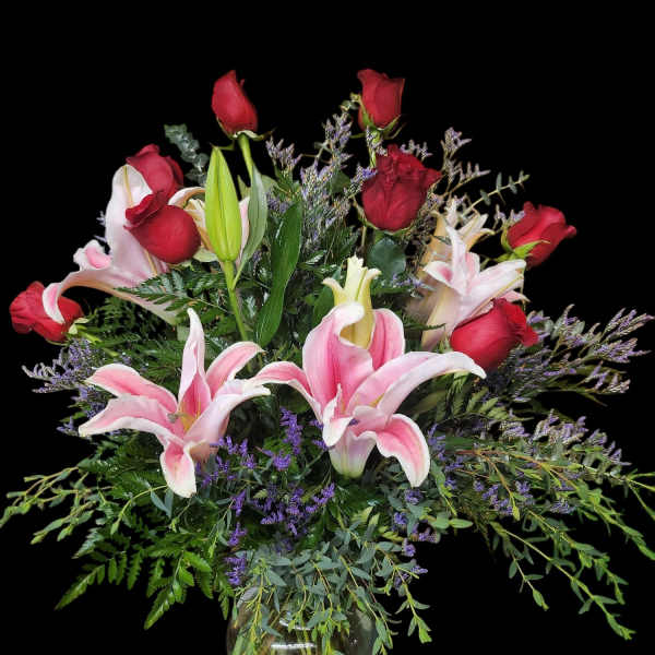 Pink lilies and red roses arranged in a glass vase