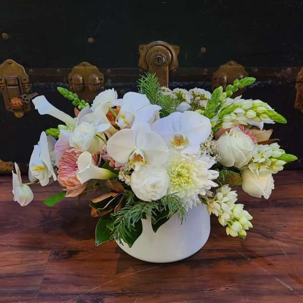 White orchids and roses arranged in a white vase