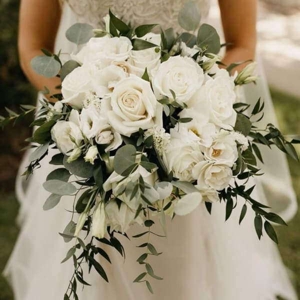 Bride holding a white rose bouquet with greenery