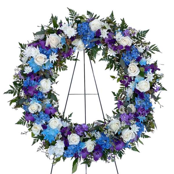 Large floral wreath with white roses, blue hydrangeas, and purple flowers