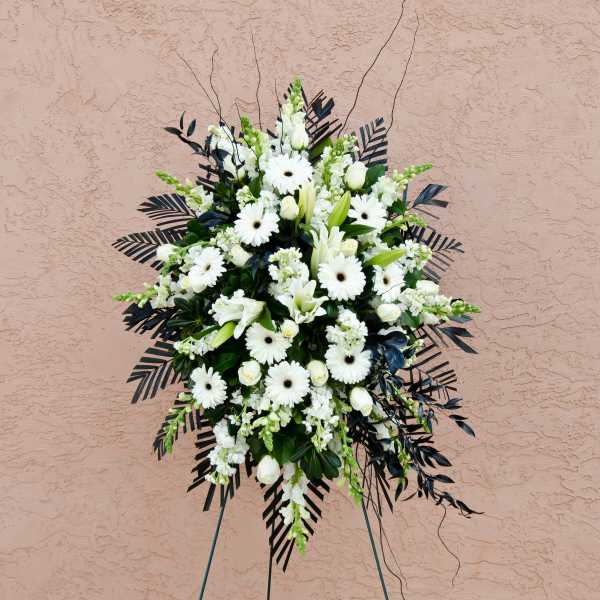White funeral spray with daisies and lilies on a stand