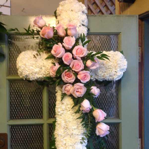 White floral cross with pink roses on a door