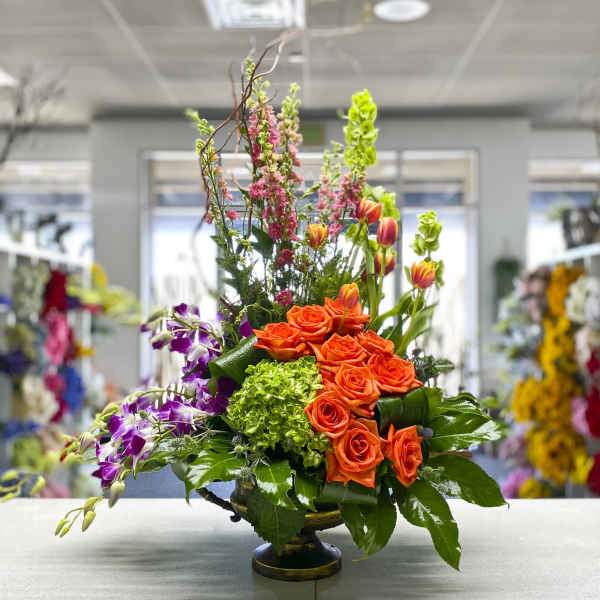 Orange roses and purple orchids in a low vase arrangement