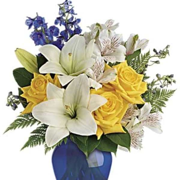 Yellow roses and white lilies in a blue vase