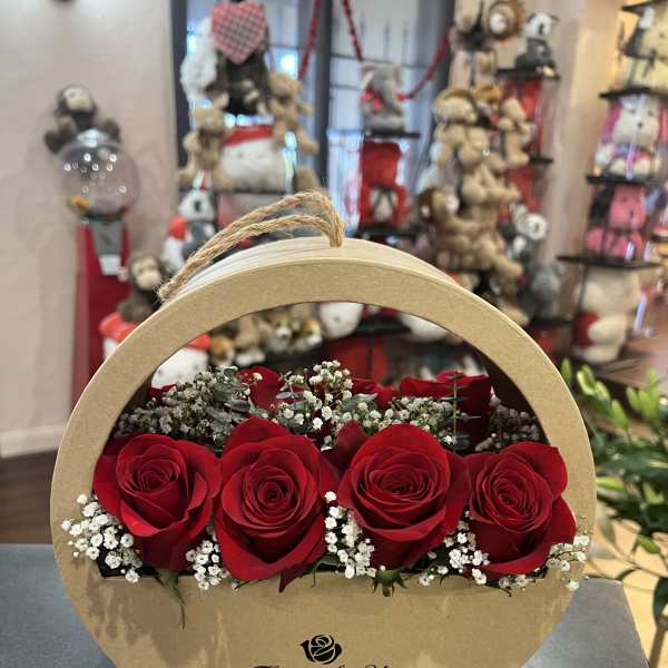 Red roses arranged in a round cardboard gift box with baby's breath
