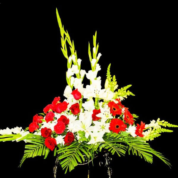 Tall floral arrangement with red roses, white lilies, and orange gerberas