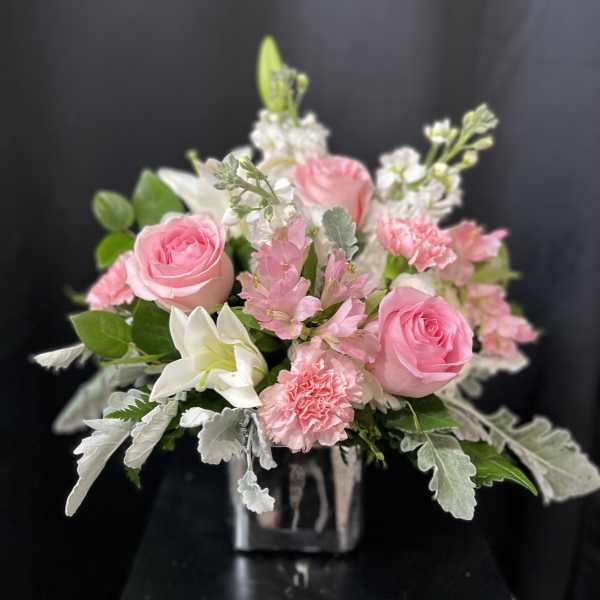 Pink roses and white lilies in a clear square vase