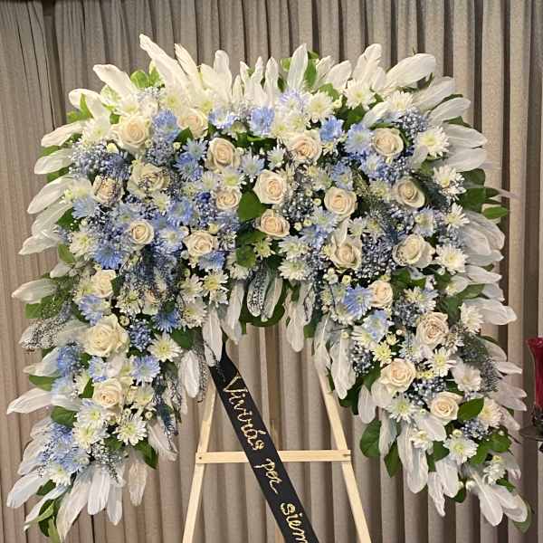 Large funeral wreath of white and blue flowers on an easel