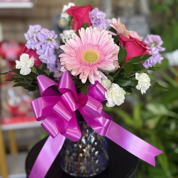 Pink gerbera bouquet with roses and carnations in a glass vase