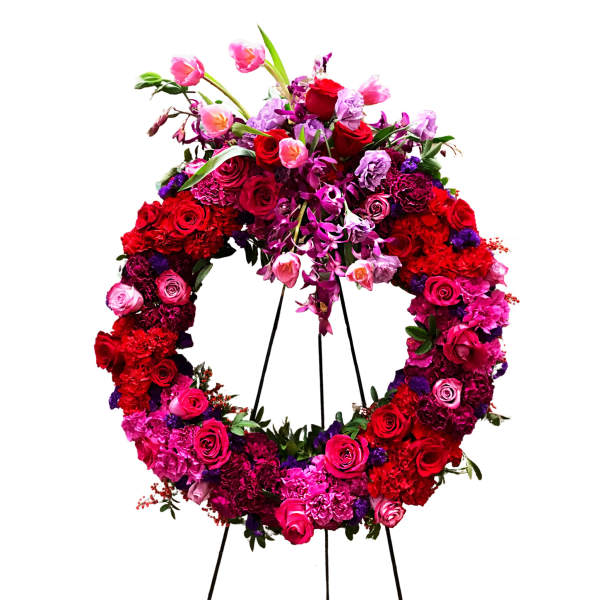 Large floral wreath on a black stand with red, pink, and purple flowers