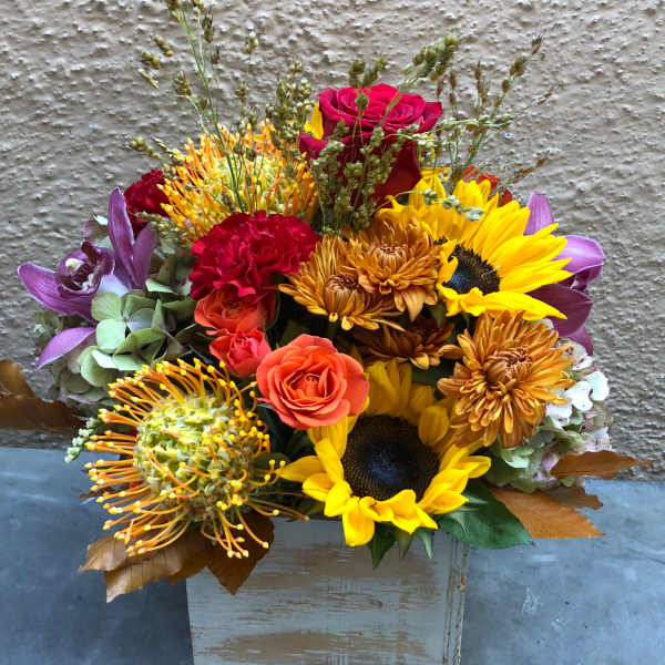Mixed bouquet with sunflowers, roses, and chrysanthemums in a wooden box