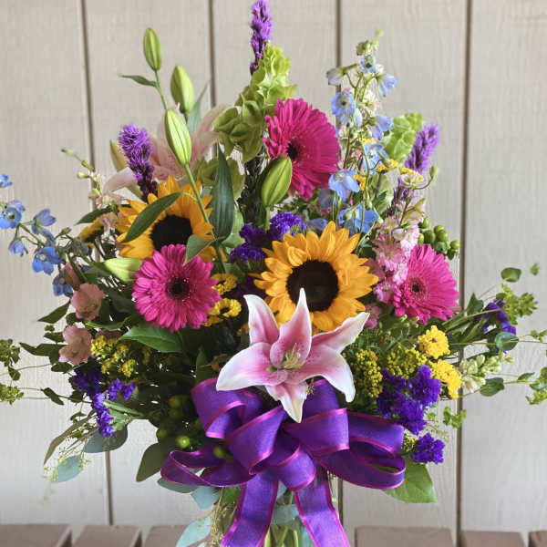 Colorful mixed bouquet in a glass vase with a purple ribbon
