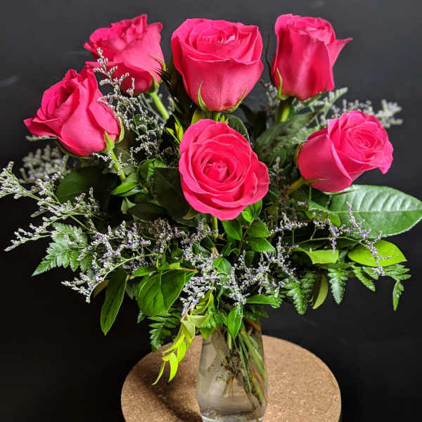 Pink roses arranged in a clear glass vase with greenery