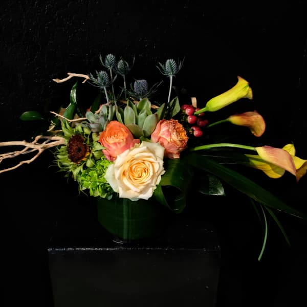 Arrangement of peach roses and yellow calla lilies in a dark vase