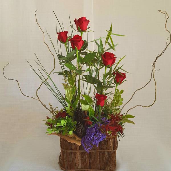 Tall arrangement of red roses in a rustic bark-covered container