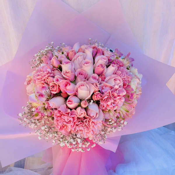 Pink rose bouquet with carnations and baby's breath wrapped in pastel paper