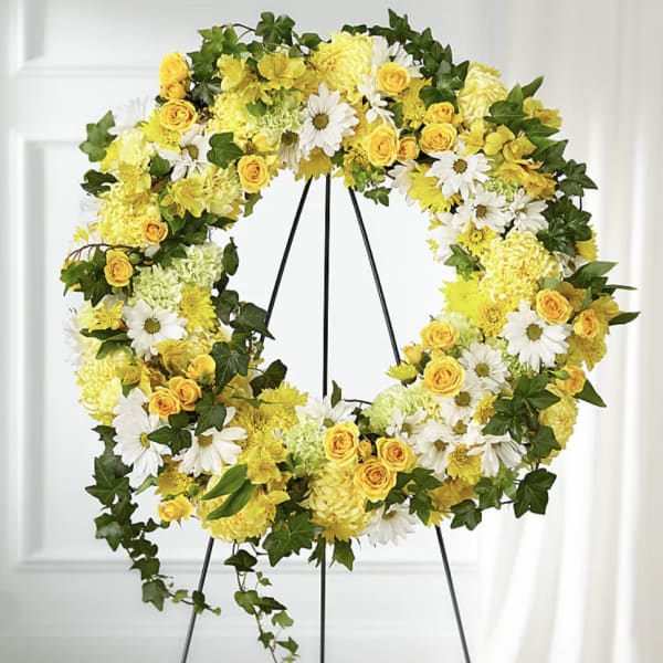 Yellow and white floral wreath on a black stand