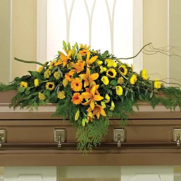 Yellow and orange floral casket spray with lilies and sunflowers