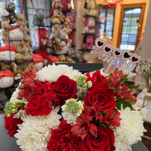 Red and white flower arrangement in a black box with a "I Love You" topper