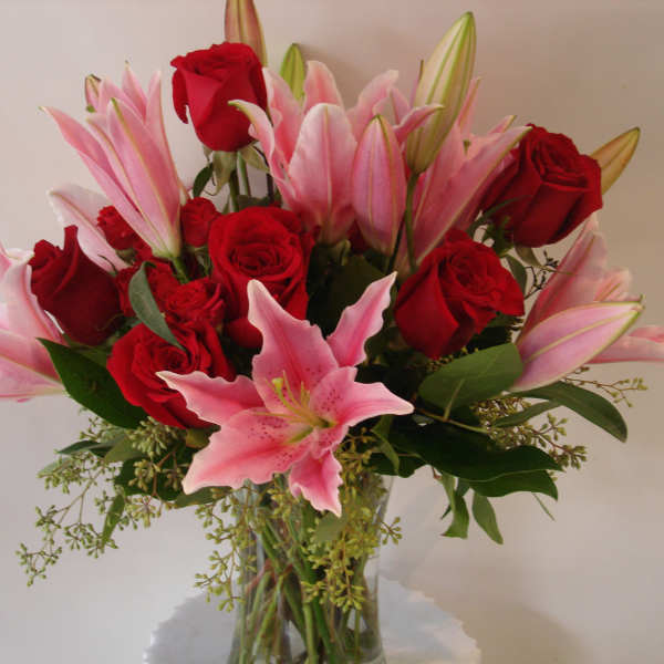 Bouquet of red roses and pink lilies in a clear glass vase
