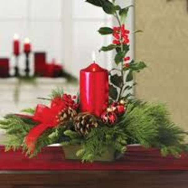 Holiday centerpiece with a red candle, pinecones, and evergreen branches