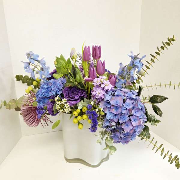 Purple and blue mixed bouquet in a white vase