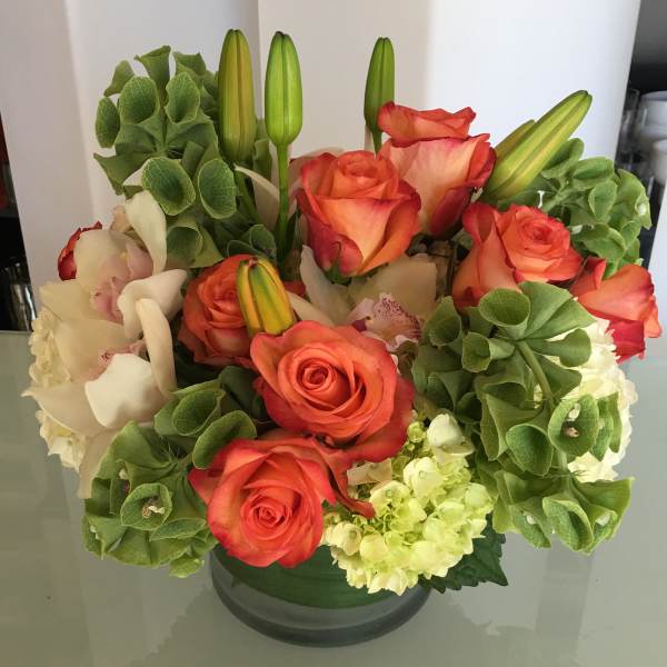 Orange roses and white lilies in a glass vase