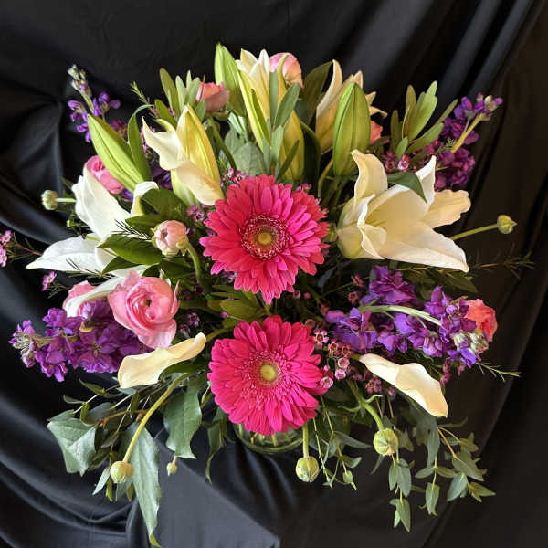Bouquet of pink gerbera daisies, white lilies, and purple flowers