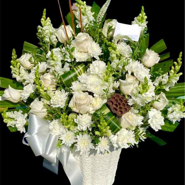 White roses and chrysanthemums in a white basket with a silver ribbon