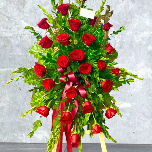 Standing spray of red roses with a pink ribbon on a tripod easel