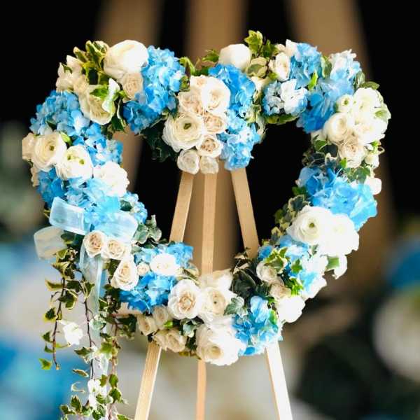 Heart-shaped floral wreath of white and blue flowers on an easel