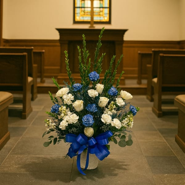 Blue and white floral arrangement with a ribbon in a church aisle