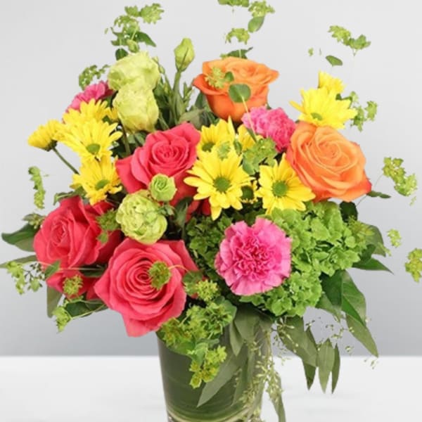 Mixed bouquet of roses, daisies, and carnations in a glass vase
